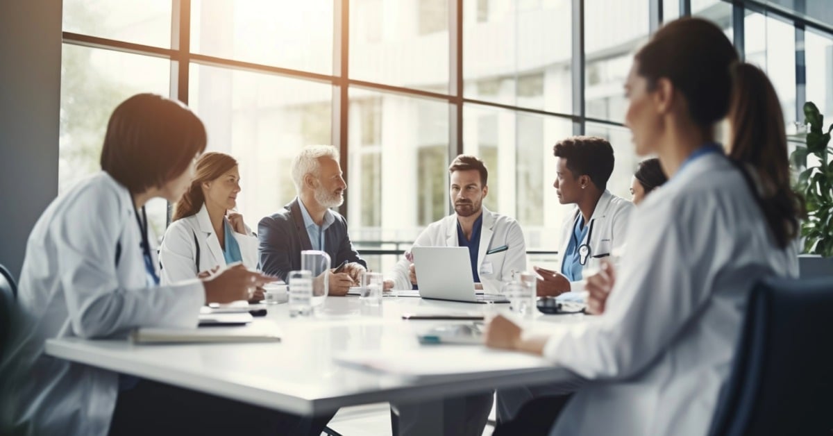 Doctors seated at a table, engaged in discussion about the CMS mandatory joint replacement payment model, CJR-X.