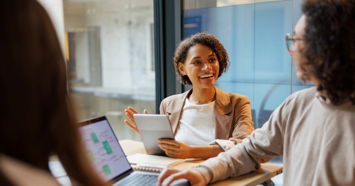 A woman and man collaborate at a table with a laptop, discussing operational aspects of CMS TEAM policies.